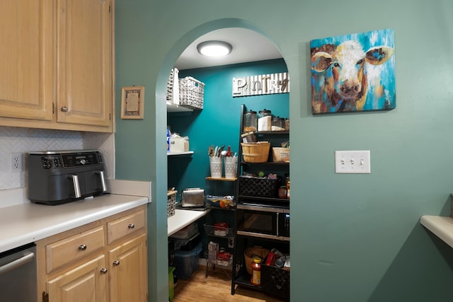 kitchen featuring tasteful backsplash, dishwasher, light wood-style flooring, light countertops, and light brown cabinetry