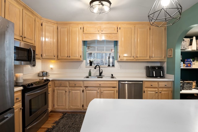 kitchen with decorative backsplash, stainless steel appliances, light countertops, light brown cabinetry, and a sink