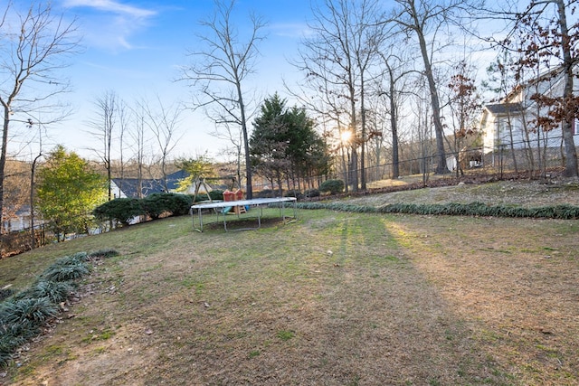 view of yard with a trampoline and fence