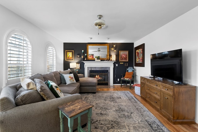 living area with light wood-style flooring, ceiling fan, and a tile fireplace