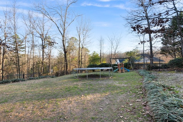 view of yard with a trampoline, fence, and a playground