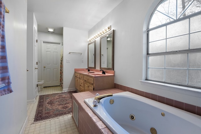 full bath featuring plenty of natural light, a sink, a jetted tub, and toilet