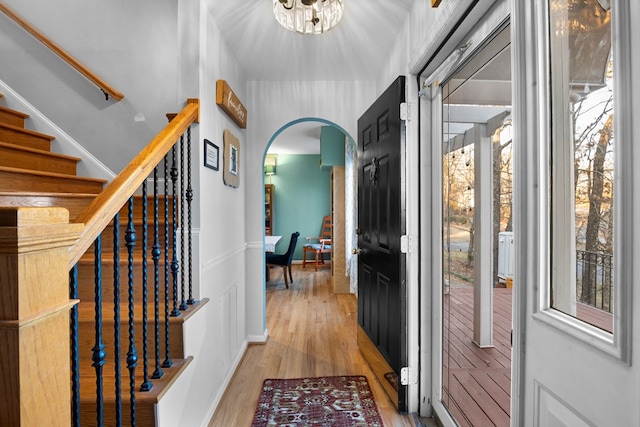 interior space featuring light wood-type flooring, an inviting chandelier, stairs, and arched walkways