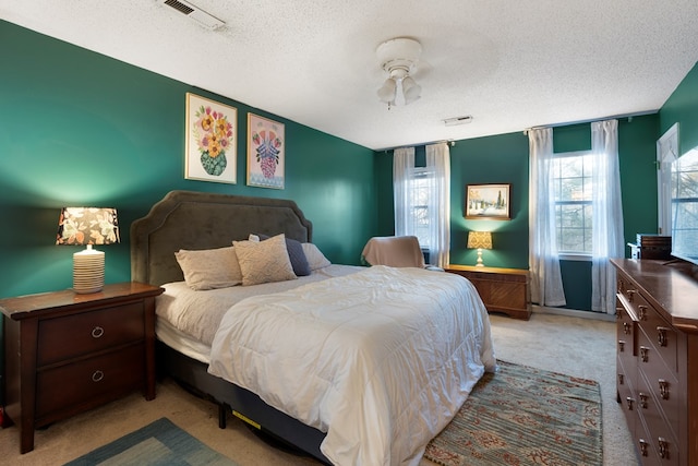 bedroom with carpet, visible vents, and a textured ceiling