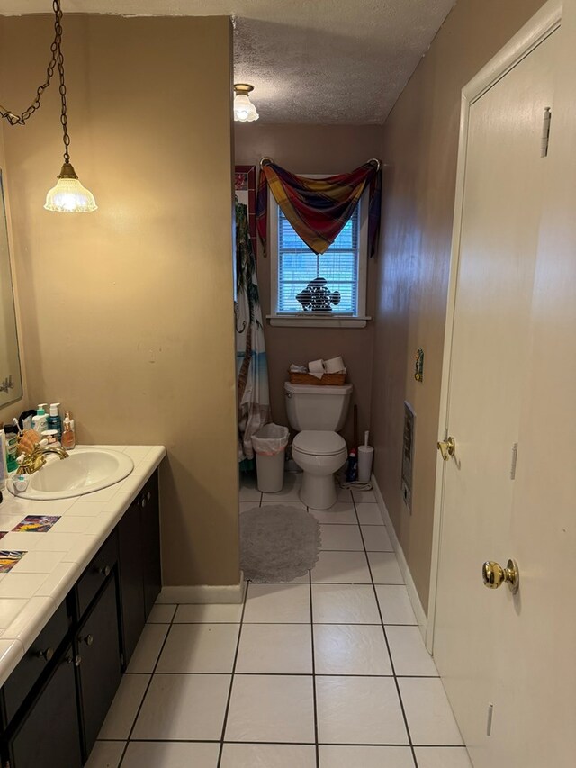 bathroom with vanity, toilet, tile patterned flooring, and a textured ceiling