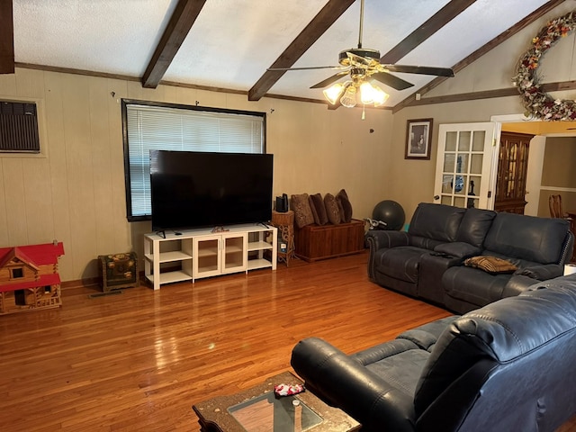 living room featuring lofted ceiling with beams, wood-type flooring, a wall mounted AC, and ceiling fan