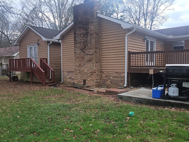 view of property exterior featuring french doors, a deck, and a lawn