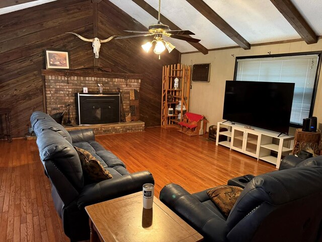 living room featuring wood walls, hardwood / wood-style floors, a brick fireplace, and vaulted ceiling with beams