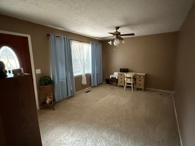 office area with ceiling fan, plenty of natural light, carpet floors, and a textured ceiling