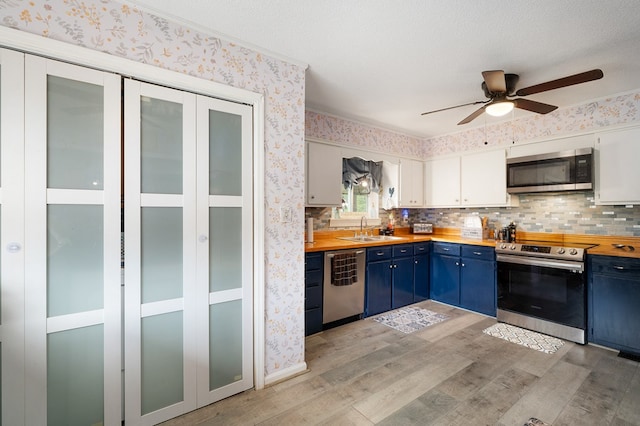 4223 Spring Valley Dr, Cohutta, GA 30710 - kitchen featuring appliances with stainless steel finishes, blue cabinets, light wood finished floors, a sink, and butcher block counters
