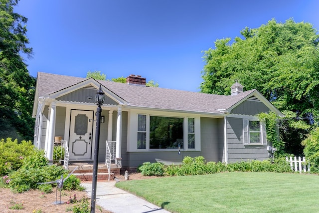 702 Lumpkin St, Dalton, GA 30720 - ranch-style house with a chimney, a porch, a front yard, roof with shingles, and board and batten siding