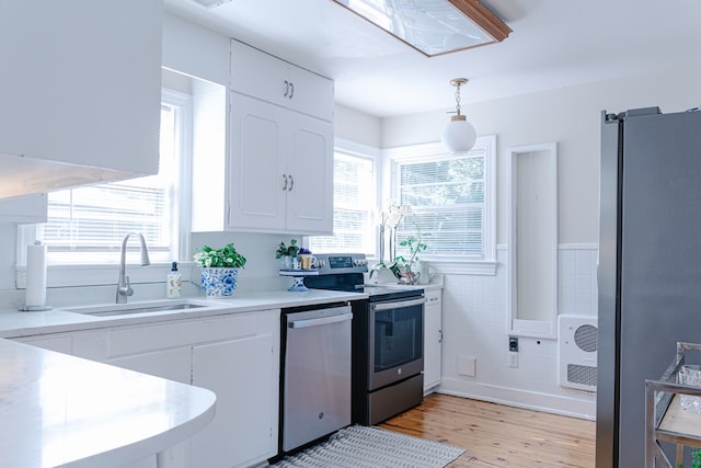 702 Lumpkin St, Dalton, GA 30720 - kitchen featuring appliances with stainless steel finishes, a sink, light wood-style flooring, white cabinetry, and a wainscoted wall