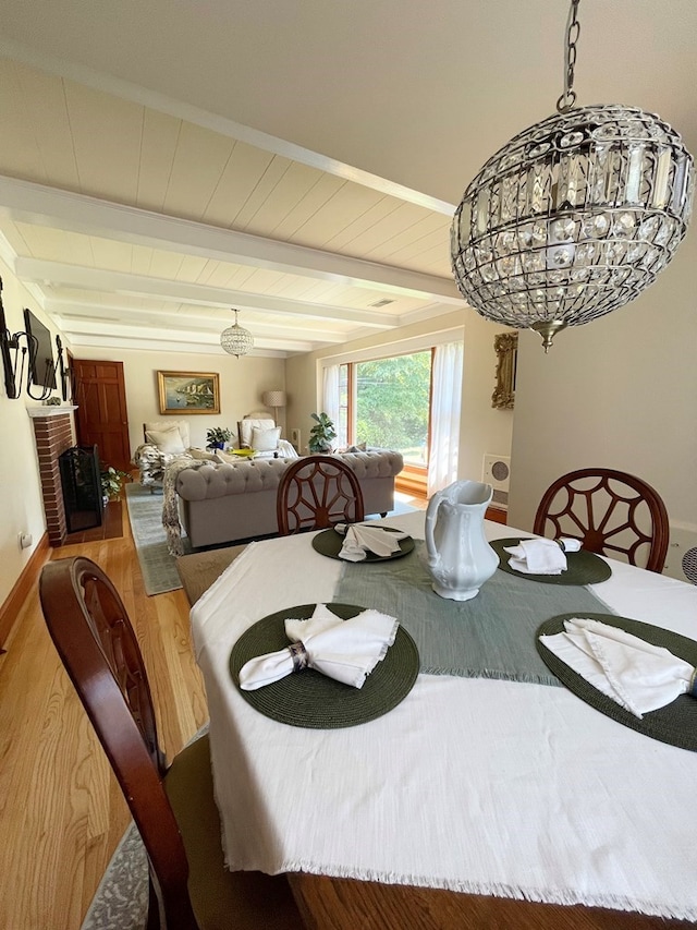 dining area featuring beamed ceiling, wood-type flooring, and a notable chandelier