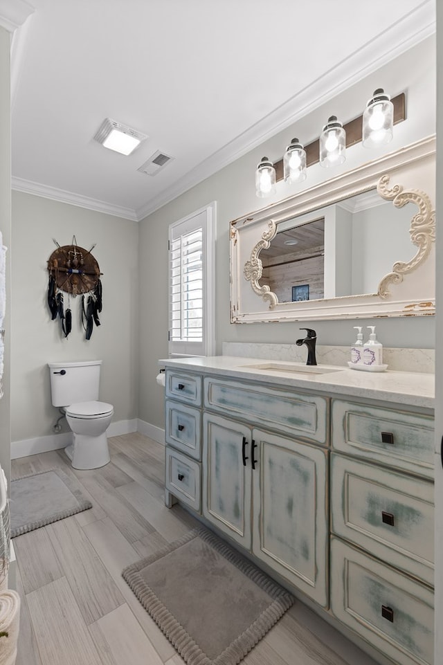 bathroom with vanity, crown molding, and toilet