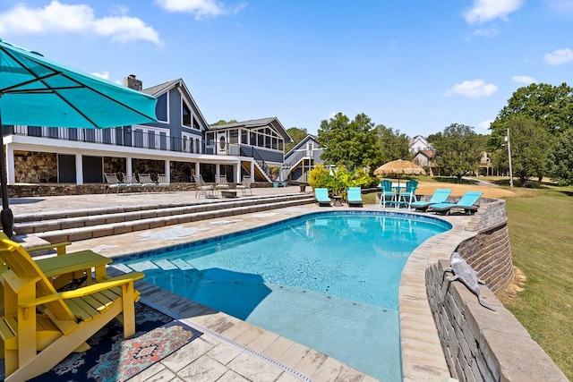 view of swimming pool featuring a yard, a patio area, and a sunroom