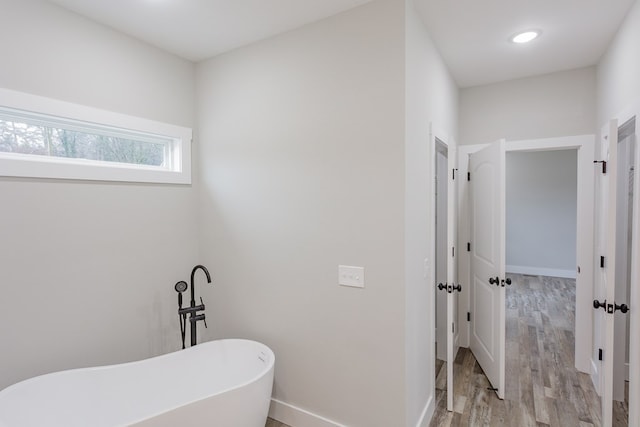 bathroom featuring wood-type flooring and a bathing tub