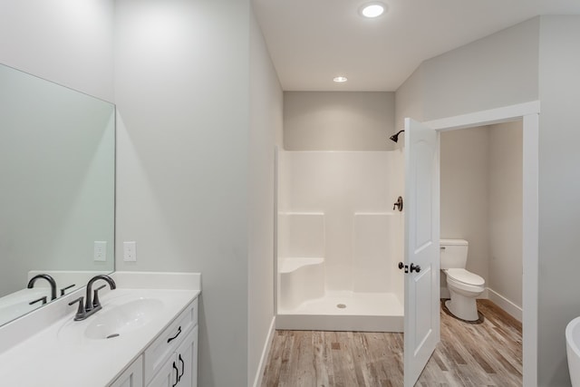 bathroom featuring vanity, wood-type flooring, toilet, and walk in shower