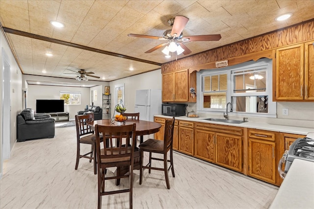 kitchen featuring freestanding refrigerator, a sink, black microwave, stainless steel gas range oven, and brown cabinets