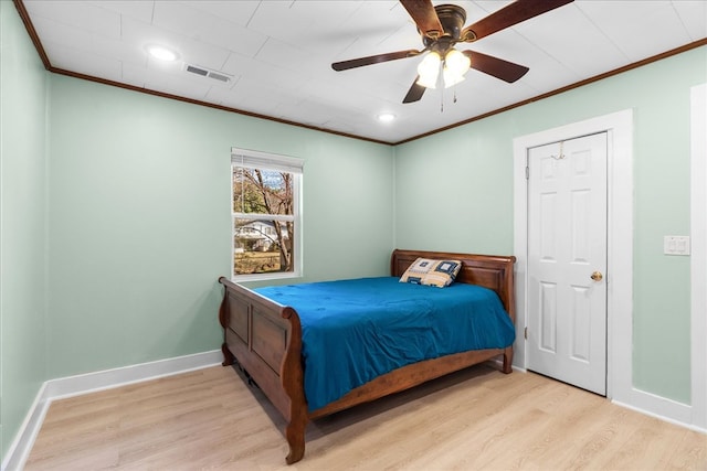 bedroom featuring visible vents, baseboards, light wood-style flooring, and crown molding