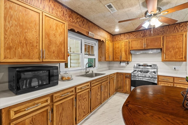 kitchen with visible vents, black microwave, under cabinet range hood, stainless steel gas stove, and a sink