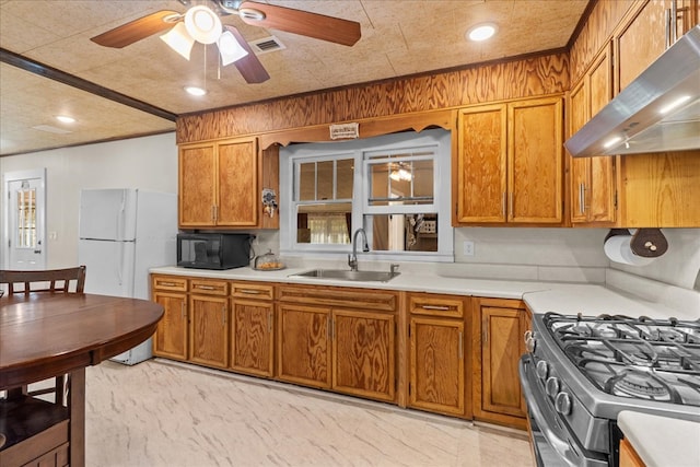 kitchen with visible vents, a sink, range with gas cooktop, black microwave, and wall chimney range hood