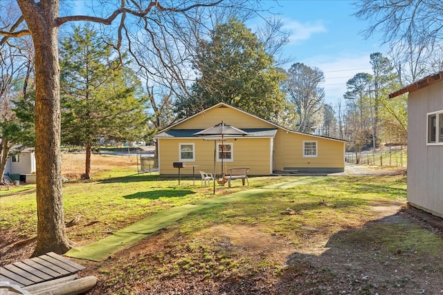 rear view of house with a lawn and fence