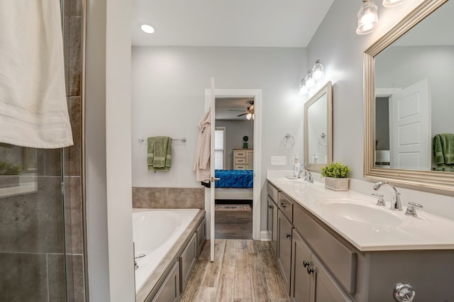 bathroom with hardwood / wood-style flooring, ceiling fan, vanity, and a tub