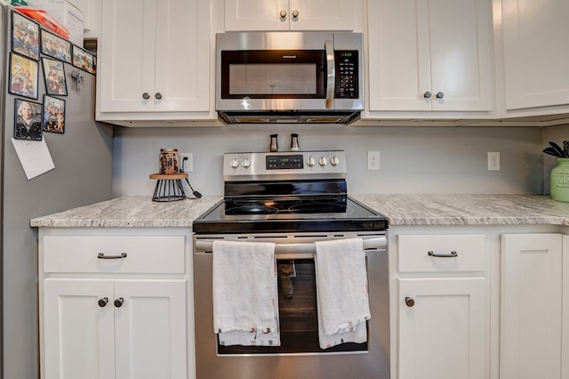 kitchen featuring light stone counters, stainless steel appliances, and white cabinets