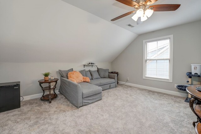 living room with ceiling fan, vaulted ceiling, and light carpet