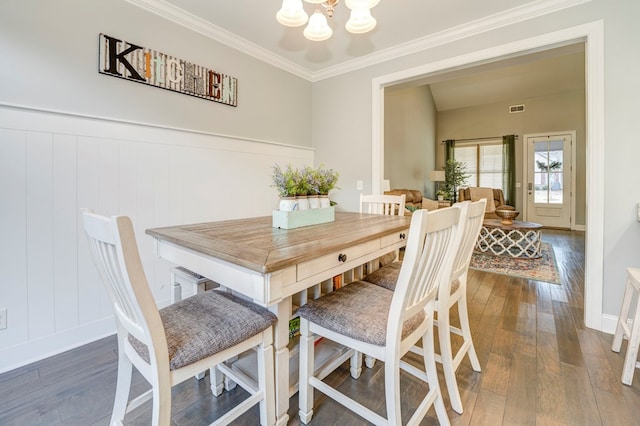 dining room featuring ornamental molding, dark wood-type flooring, and an inviting chandelier