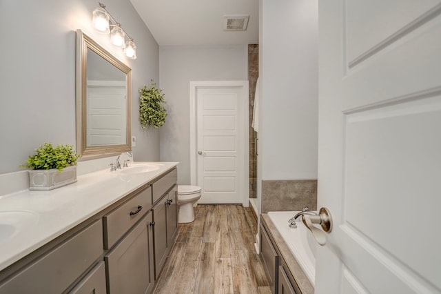 bathroom featuring a washtub, vanity, hardwood / wood-style flooring, and toilet