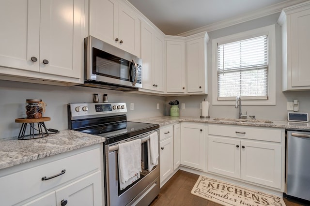 kitchen featuring stainless steel appliances, white cabinetry, sink, and light stone counters