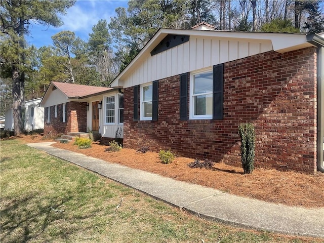 view of front of property featuring brick siding, a front lawn, and board and batten siding