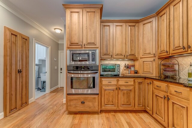 27 Bluff Mountain Dr, Rome, GA 30165 - kitchen featuring appliances with stainless steel finishes, decorative backsplash, dark stone countertops, light wood-style flooring, and ornamental molding