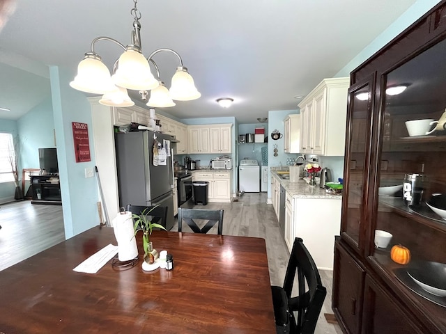 609 Charles St, Dalton, GA 30720 - dining area featuring light wood-style flooring, a chandelier, and washing machine and clothes dryer