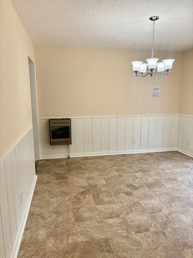 139 Hills Dr, Cohutta, GA 30710 - empty room with heating unit, a textured ceiling, a wainscoted wall, and a chandelier