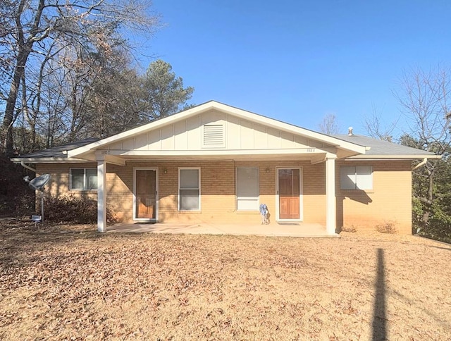 back of property featuring a patio, board and batten siding, and brick siding