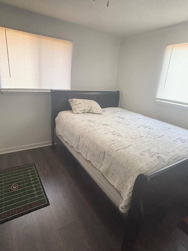 bedroom featuring a textured ceiling, baseboards, and dark wood-type flooring