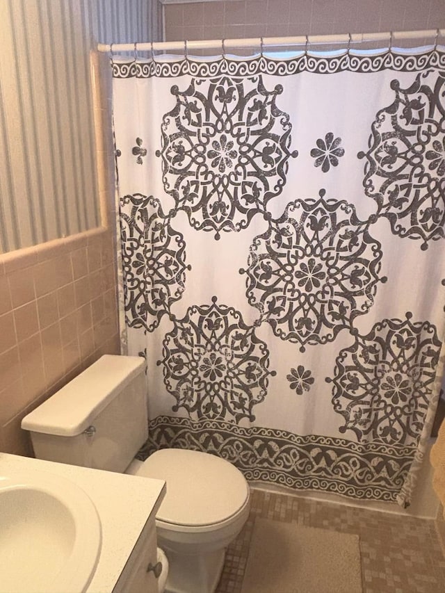 full bath with tile walls, vanity, and toilet