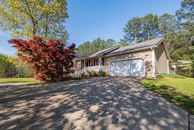 view of front of house with an attached garage, covered porch, driveway, and a front yard