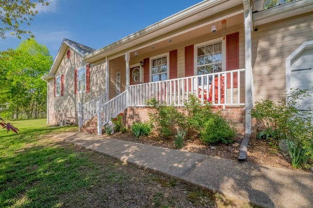 doorway to property featuring covered porch and a yard