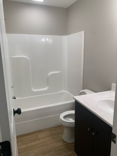 full bathroom featuring hardwood / wood-style flooring, vanity, bathtub / shower combination, and toilet