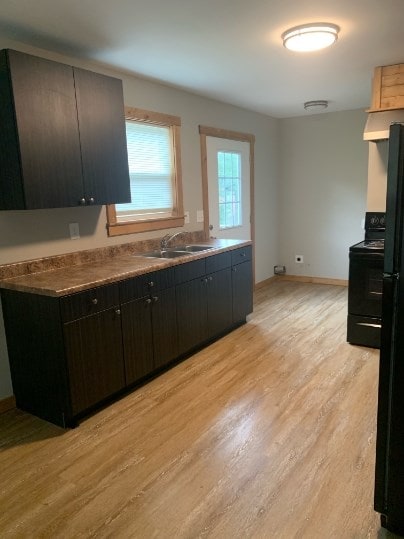 kitchen with sink, black appliances, and light hardwood / wood-style floors