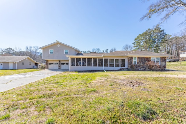 view of front facade with a garage, concrete driveway, a front lawn, and a sunroom