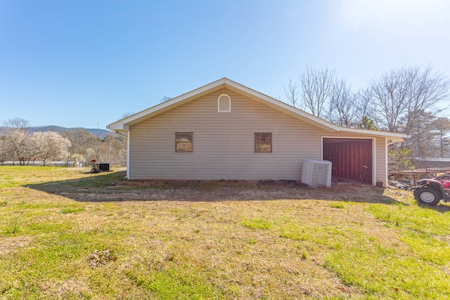 view of side of property with a lawn, a mountain view, and a garage