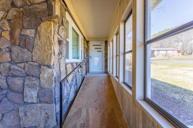 view of front of property with stone siding, concrete driveway, a front lawn, and a sunroom