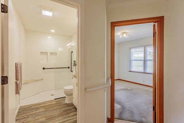 full bathroom with toilet, ornamental molding, wood finished floors, tiled shower, and baseboards