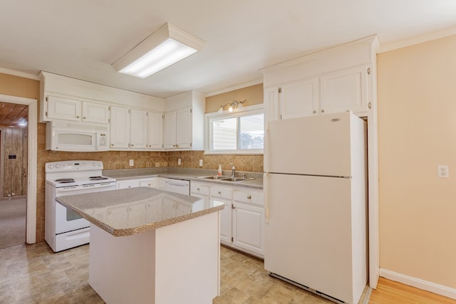 kitchen with white cabinets, white appliances, a center island, and a sink