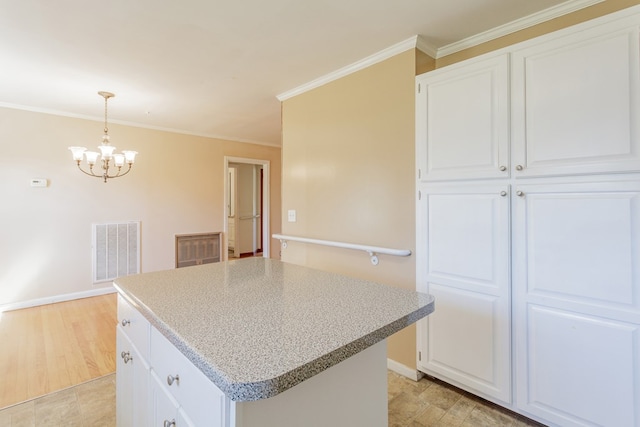 kitchen with visible vents, a kitchen island, crown molding, and white cabinetry