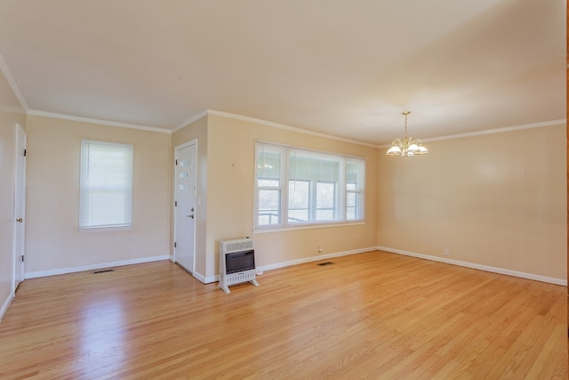 empty room with heating unit, a chandelier, light wood finished floors, and crown molding